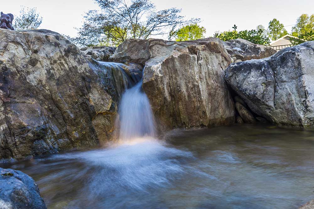 A JVI ecosystem pond with a large waterfall pouring between boulders