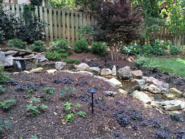 A small winding stream cutting through a planted natural area.