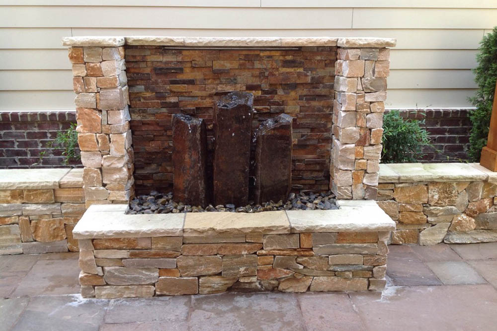 Three basalt column fountains built into a stone wall.