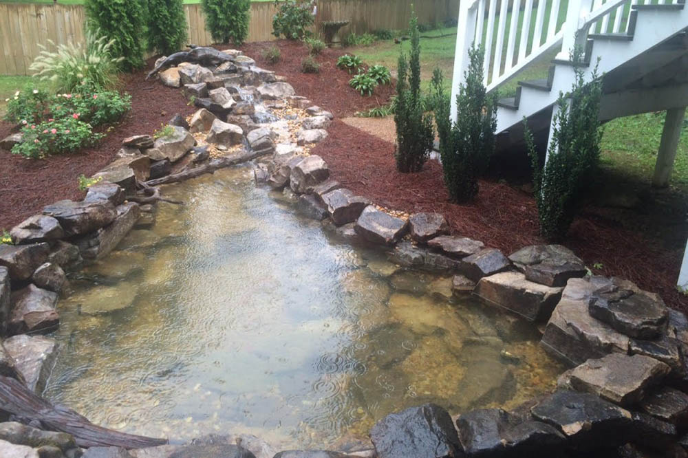 A small stream beside a walkway, water running clear after service