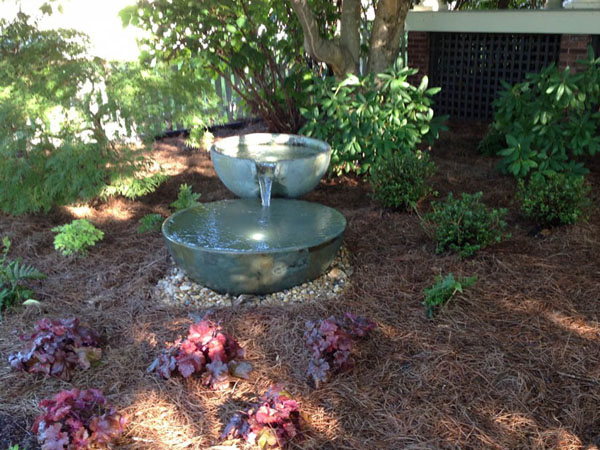 Tiered spillway bowl fountain set into a planted natural area